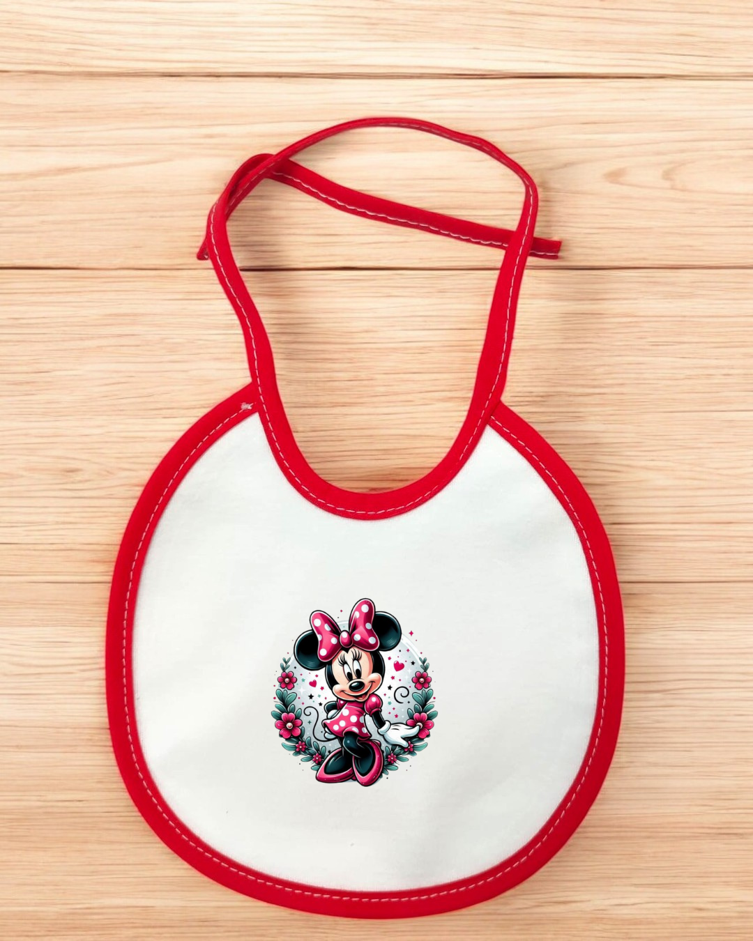 Babete de bebé com ilustração da Minnie Mouse e acabamento vermelho sobre fundo branco