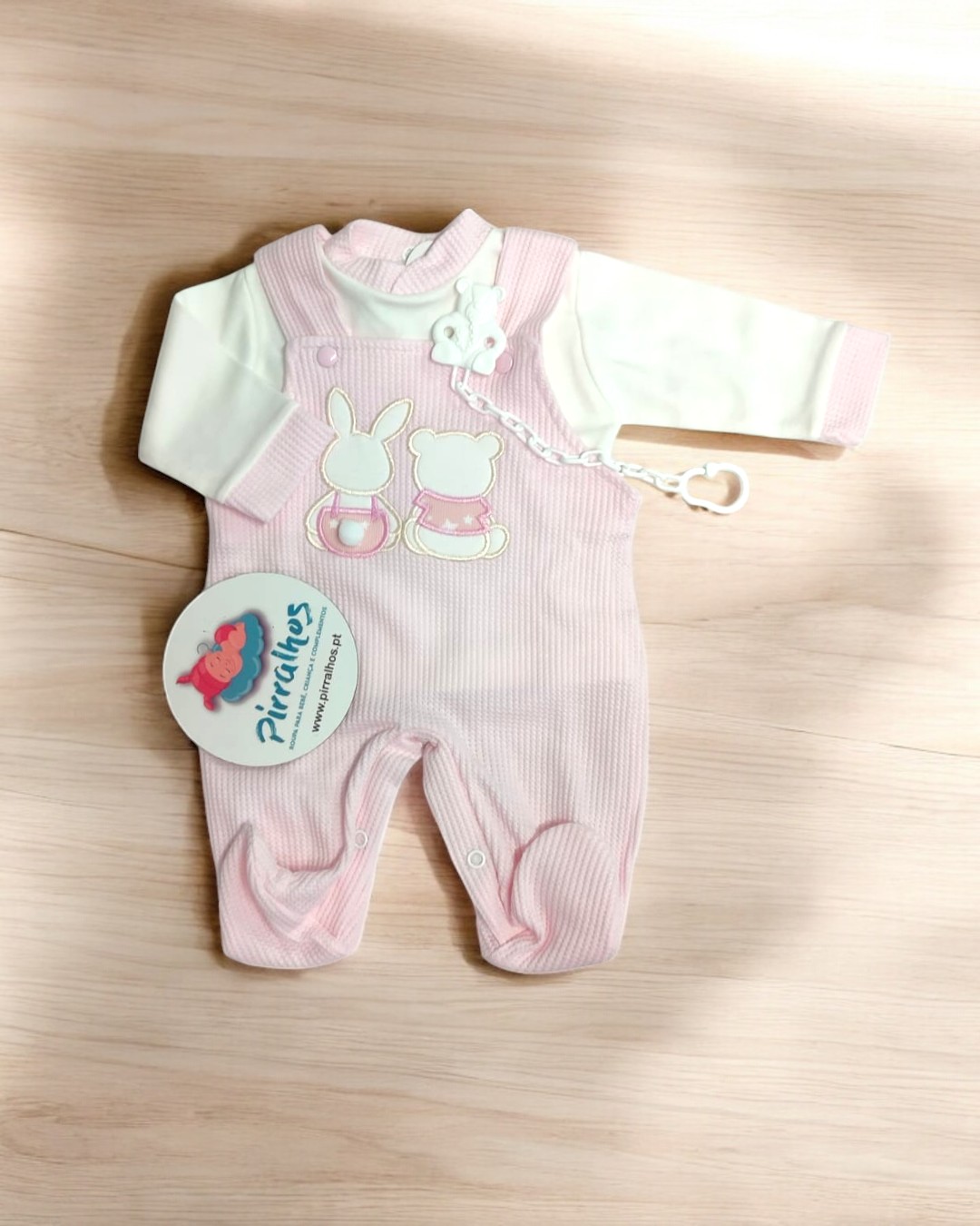 Conjunto de bebé com body branco e salopete rosa com aplicações e etiqueta da marca