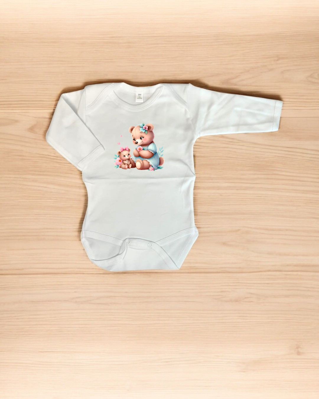 Body branco de bebé com estampa de ursos cor-de-rosa sentado em fundo de madeira