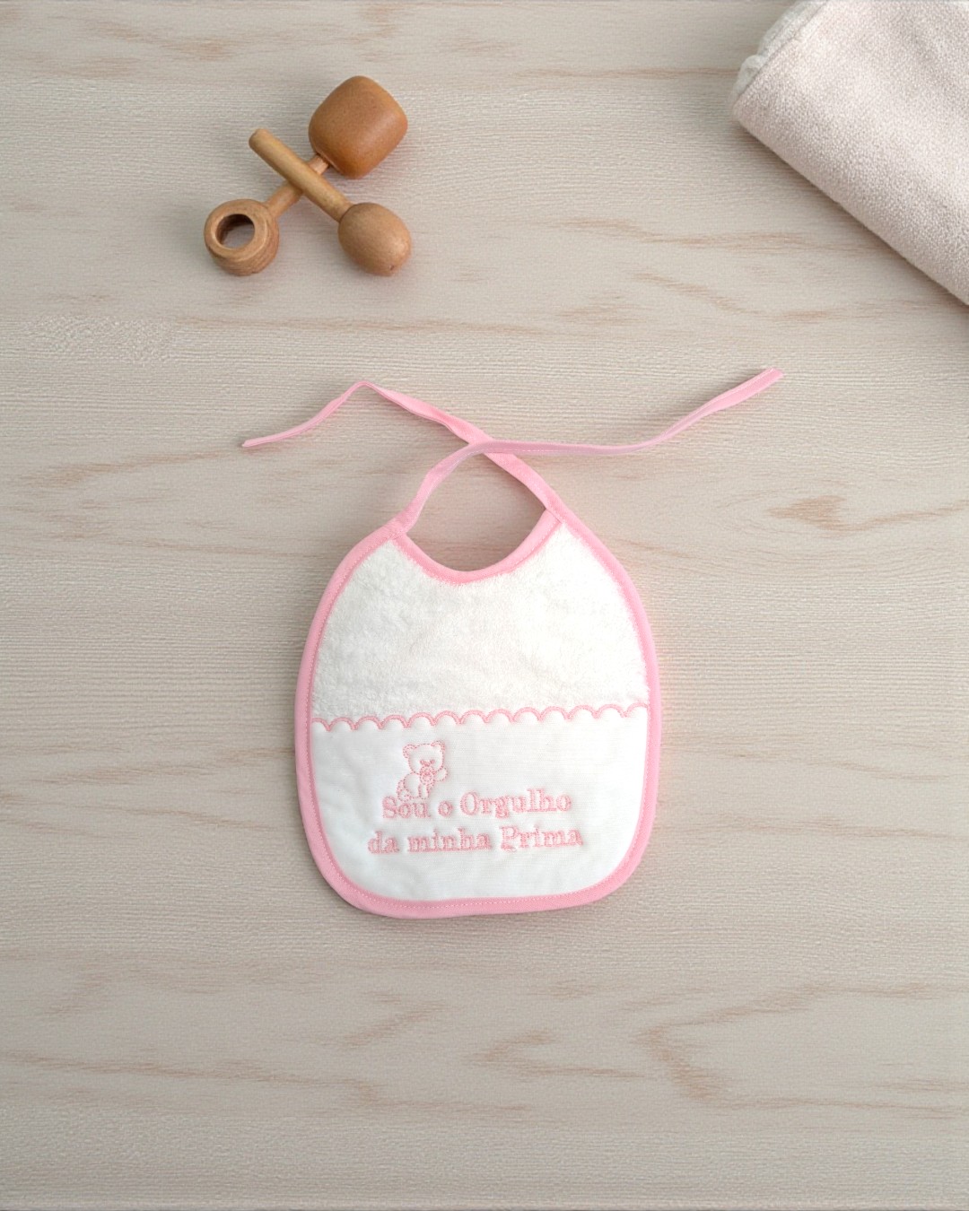 Babete branco e rosa com bordado e texto em madeira clara com brinquedo de madeira e tecido