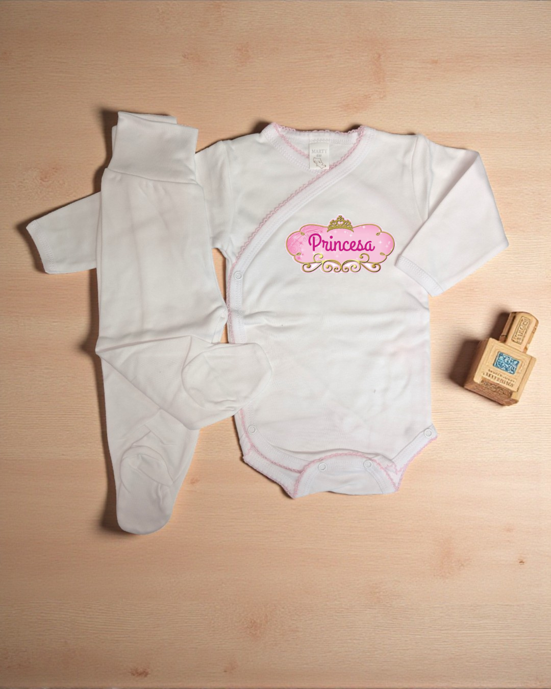 Conjunto de roupa de bebé branco com body e meias em superfície de madeira