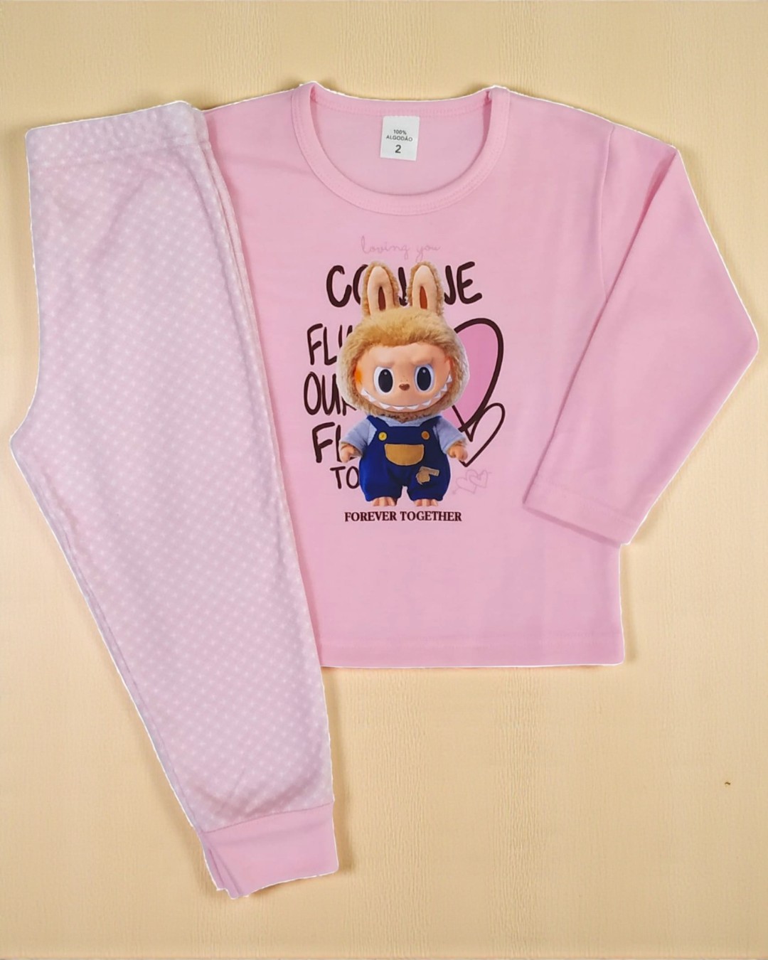 Conjunto de pijama rosa para criança com estampa de boneco e calças com padrão de bolinhas