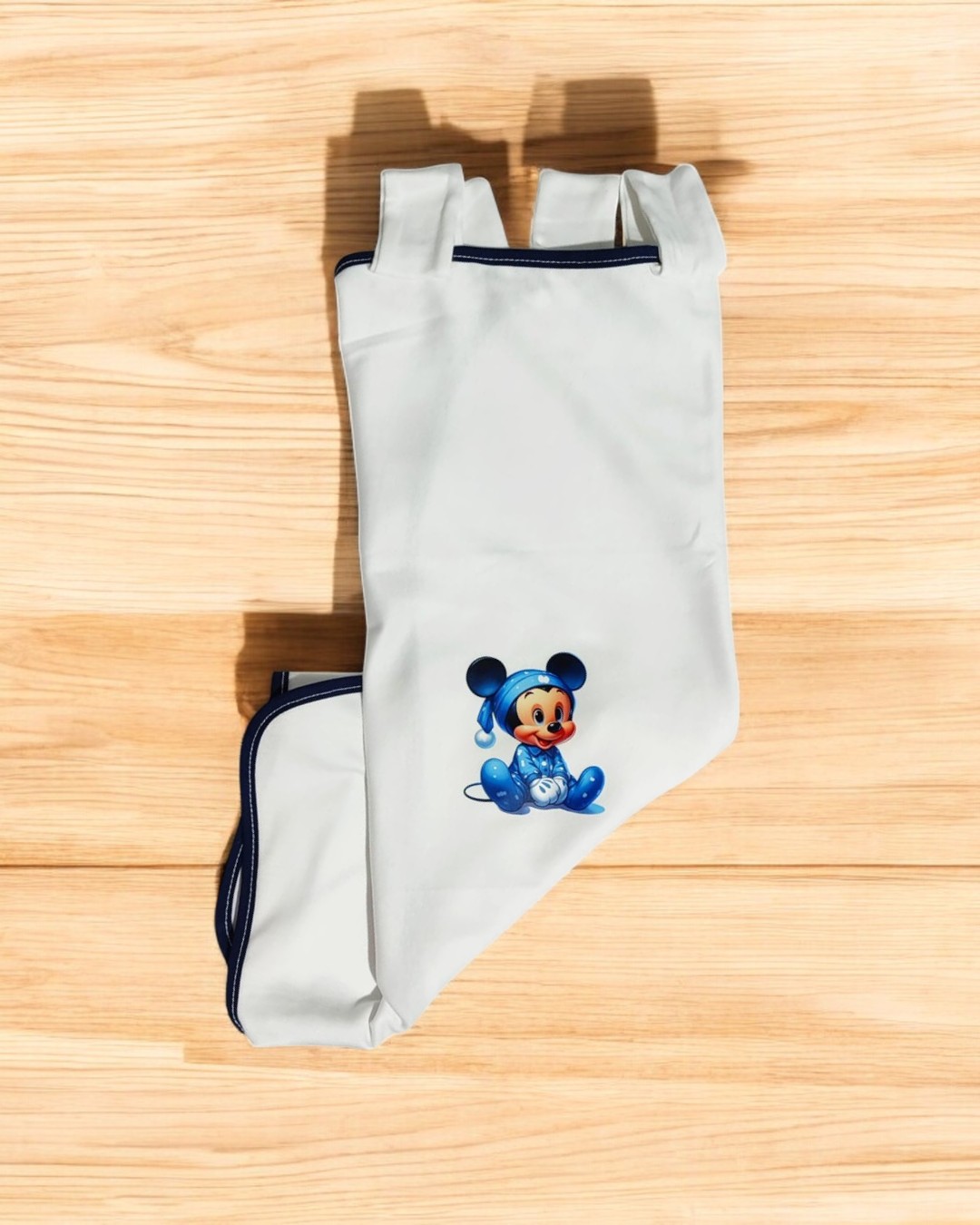 Luvas brancas com estampa do Mickey Mouse em roupa azul sobre fundo de madeira clara