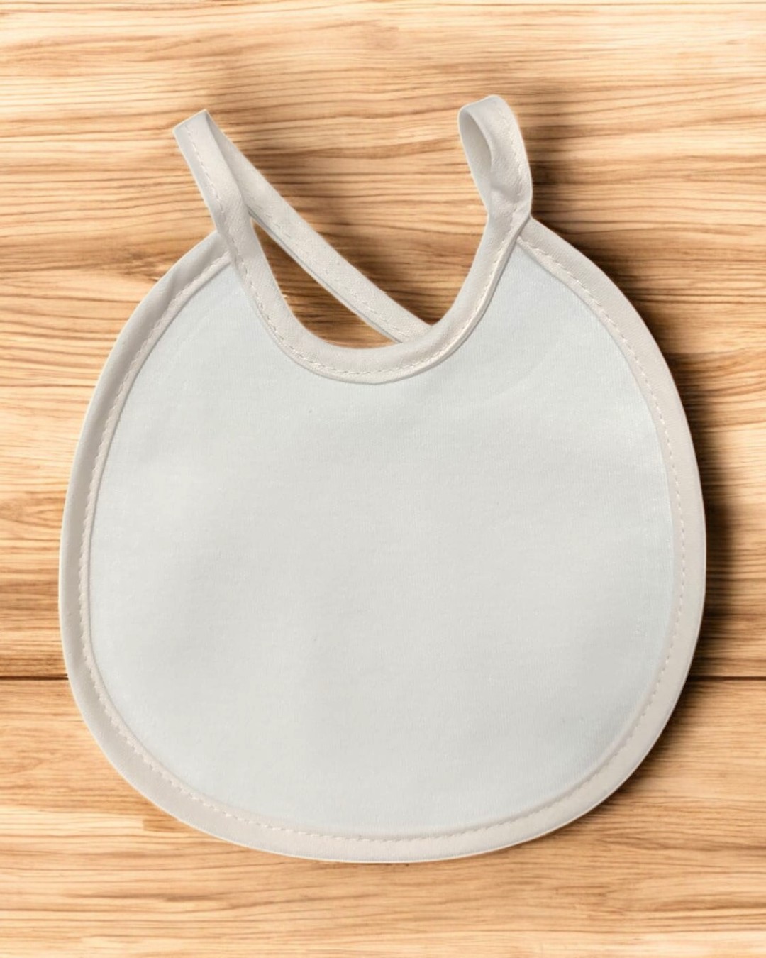 Babete redondo branco com duas alças sobre superfície de madeira