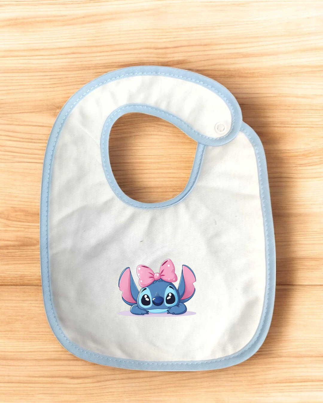 Babete branco com bordas azuis e desenho da personagem Stitch com laço cor-de-rosa