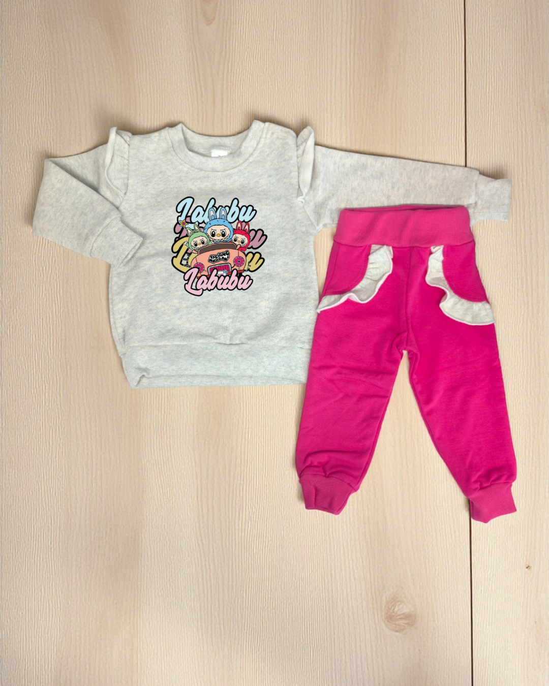 Conjunto infantil com camisola cinzenta estampada e calças rosa com detalhes cinzentos