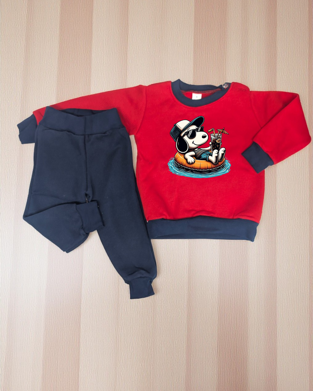 Conjunto de roupa infantil vermelha e azul escura com estampado de cão relaxando numa boia