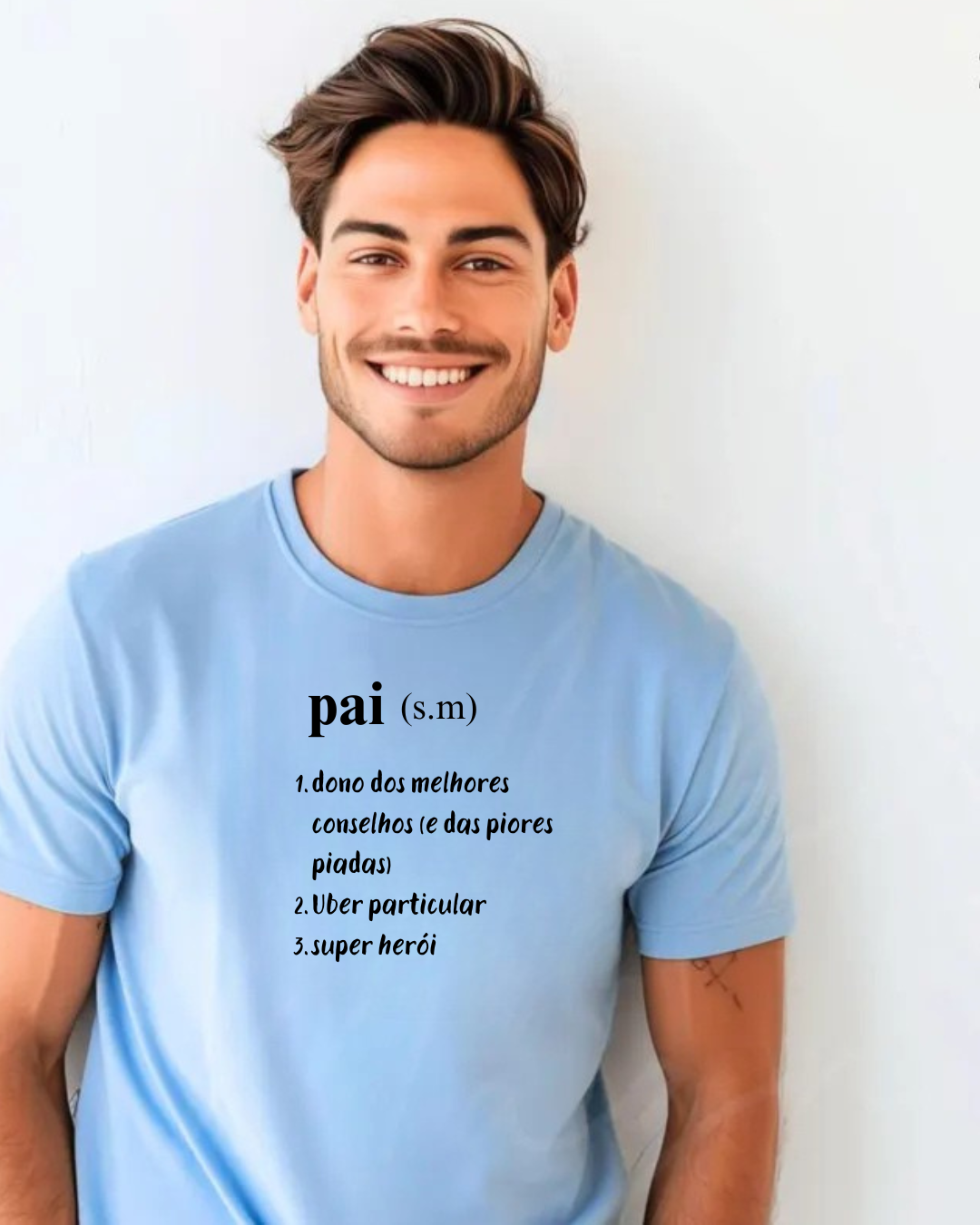 Homem sorridente veste camiseta azul clara com texto em preto 'pai (s.m) 1. dono dos melhores conselhos (e das piores piadas) 2. Uber particular 3. super herói' em fundo branco
