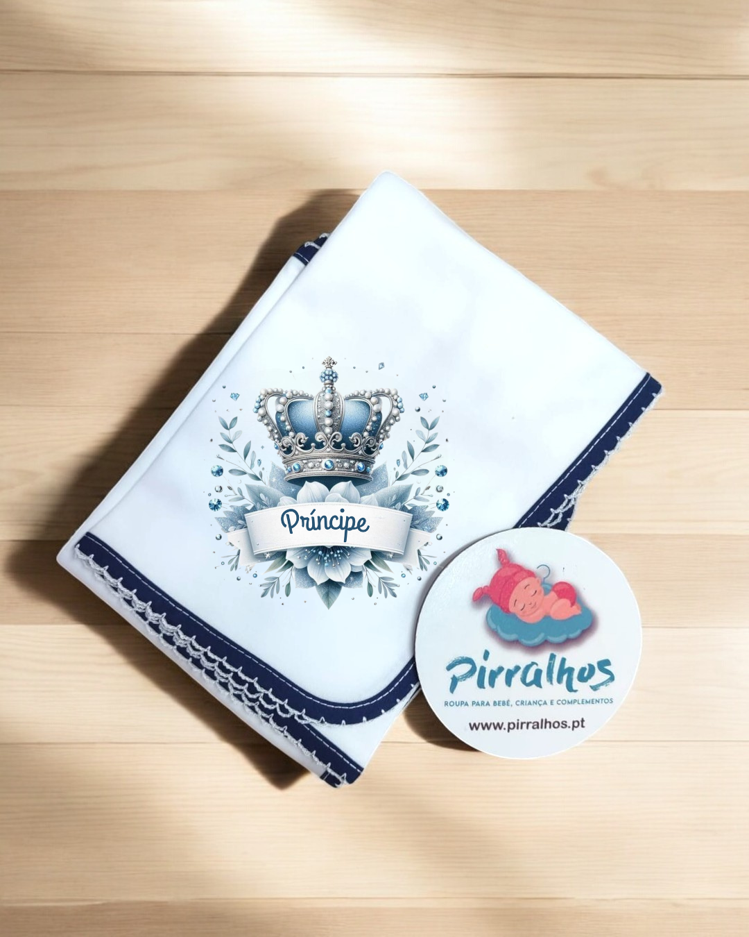 Fralda branca com coroa azul e palavra Príncipe, etiqueta Pirralhos ao lado