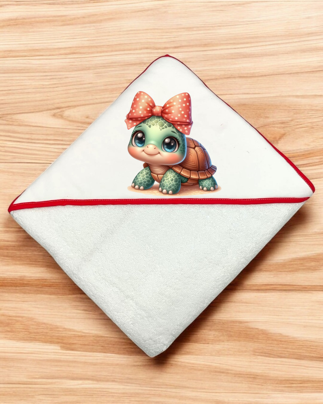 Toalha branca para bebé com bordas vermelhas e tartaruga verde com laço vermelho.