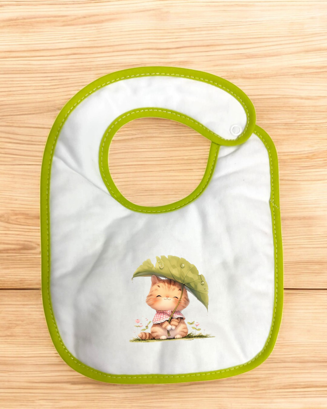 Babete branco com borda verde e desenho de gato com folha