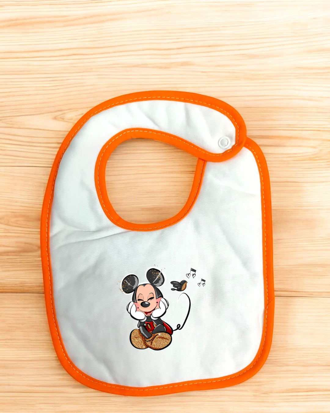 Babete branco com borda laranja e desenho de rato animado a cantar