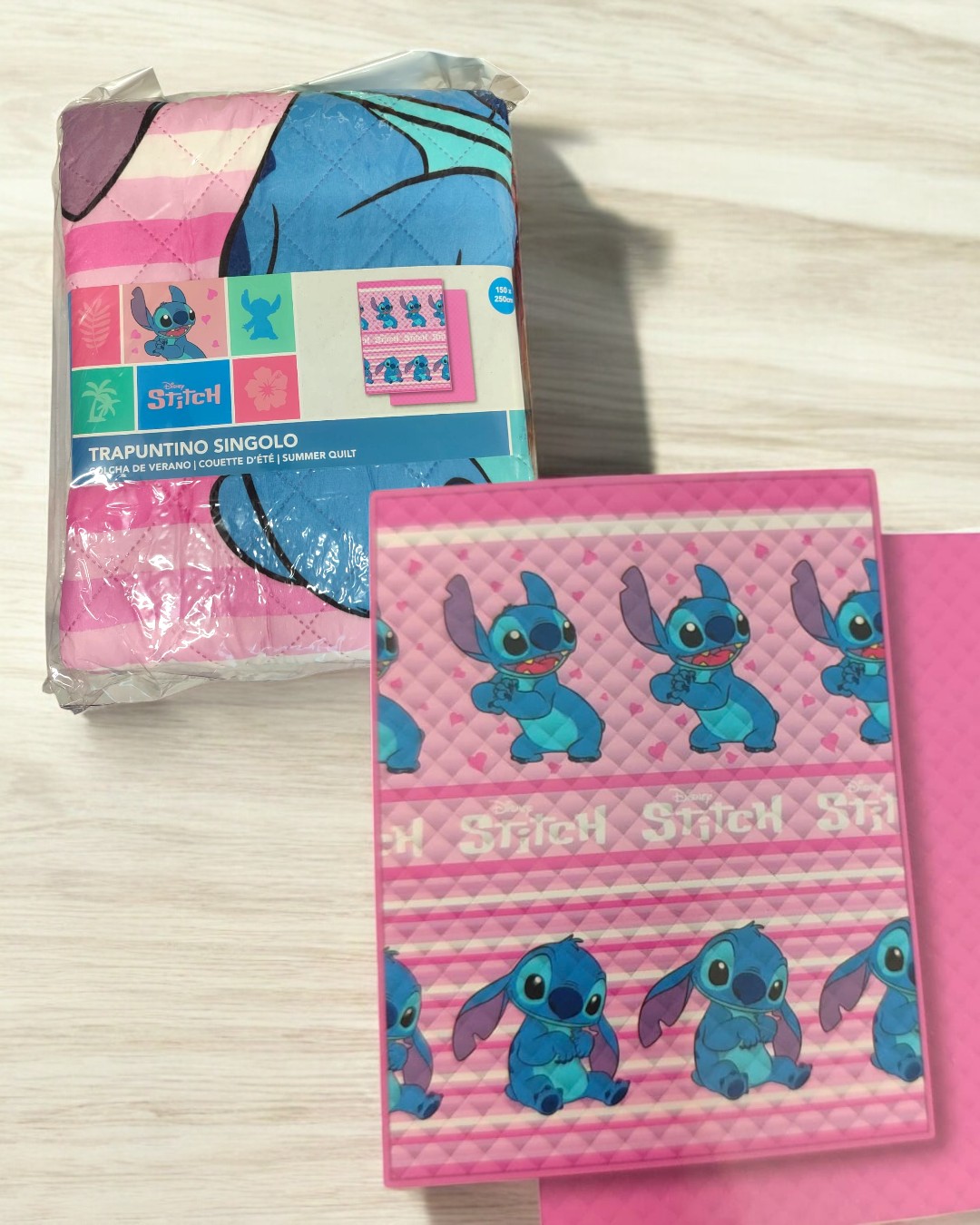 Edredão rosa com personagens Stitch azuis e embalagem com etiqueta.
