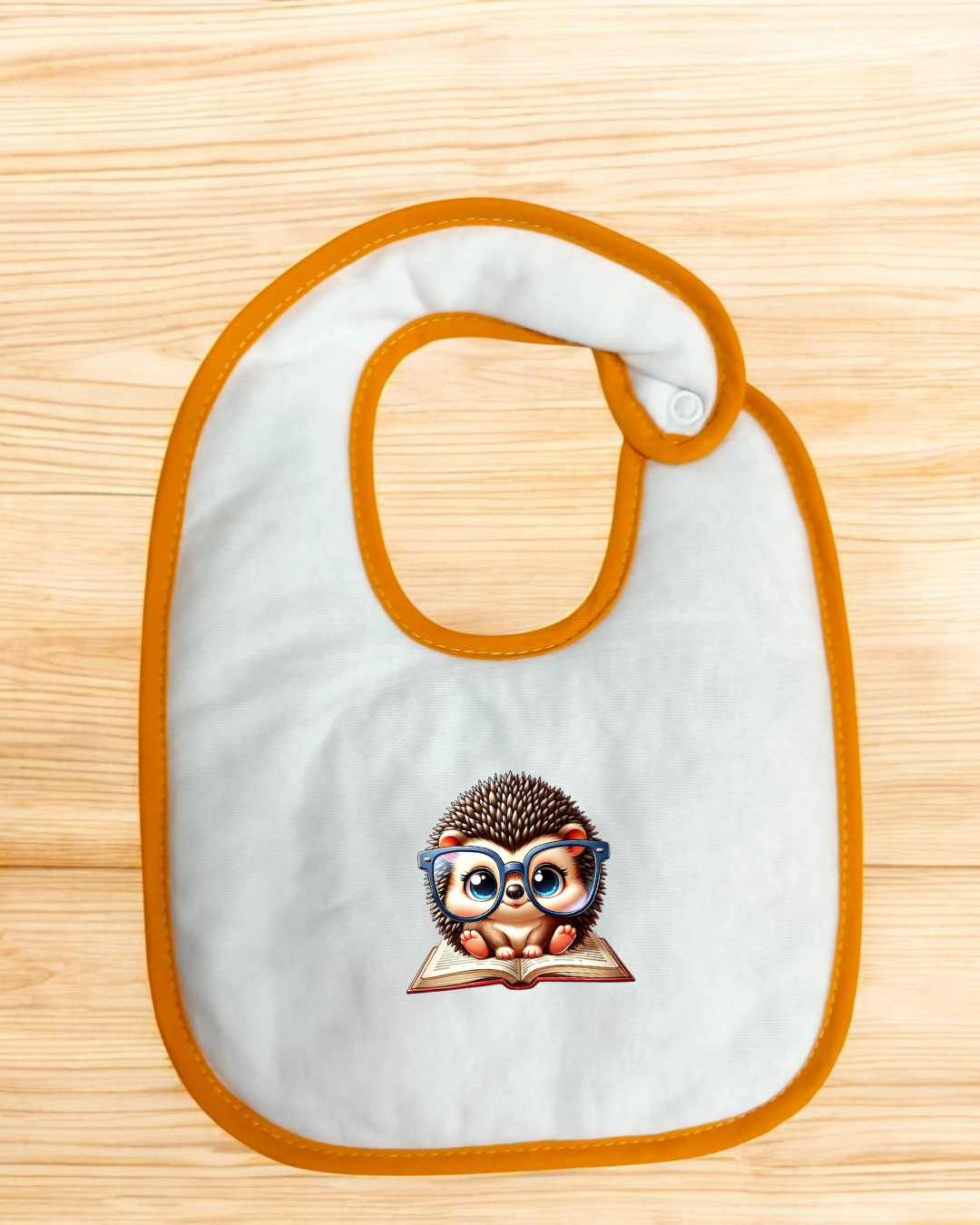 Babete branco com borda laranja e imagem de ouriço com óculos lendo livro