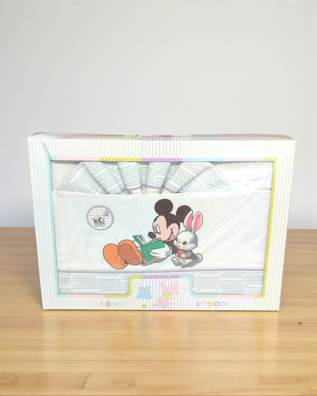 Jogo de cama infantil branco com imagem de Mickey Mouse e coelho numa caixa com visor.
