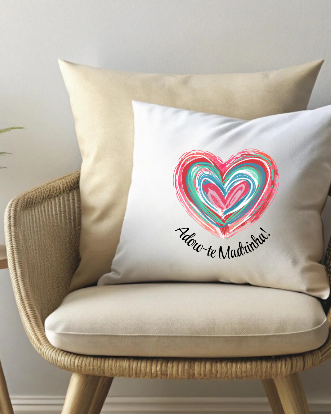 Almofada branca com coração colorido e texto sobre cadeira de vime.