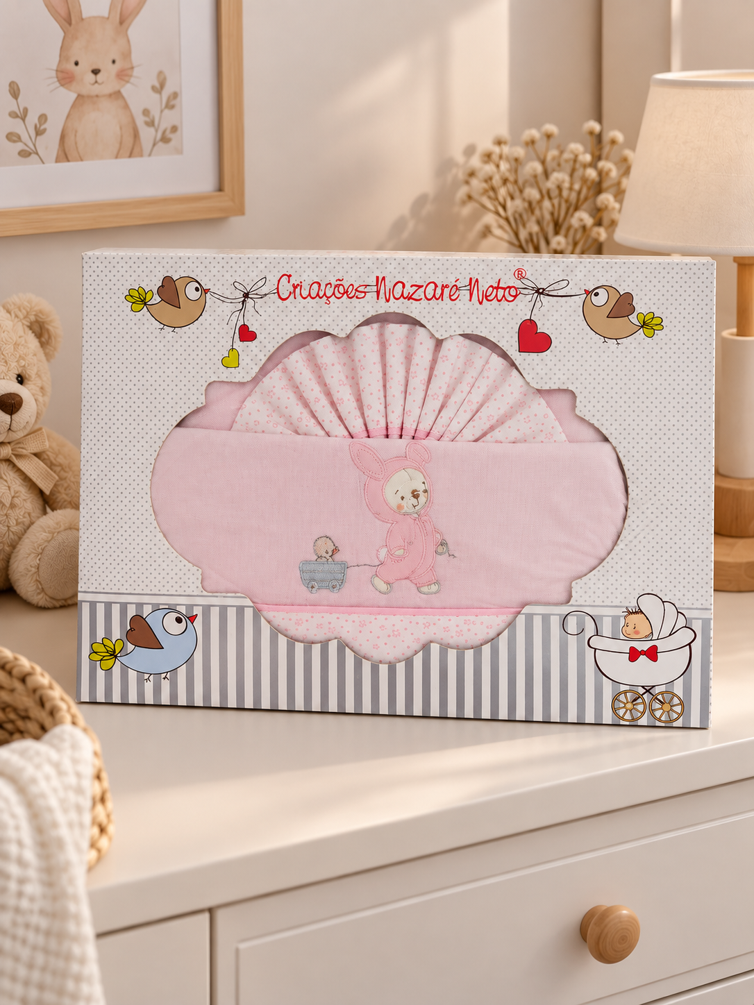 Conjunto rosa para bebé com padrão de pequenas flores em embalagem decorada com pássaros e texto Criações Nazaré Neto