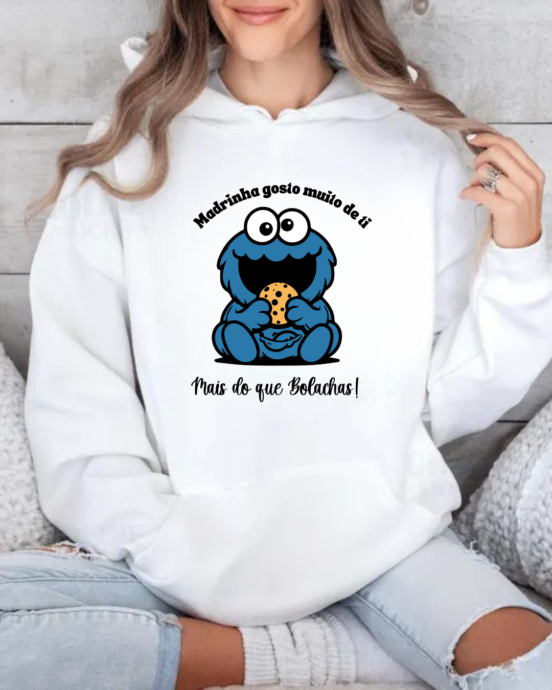 Sweatshirt branca com estampa de monstro azul segurando bolacha e texto em português.