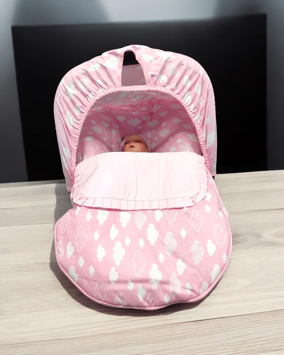 Porta-bebé rosa com padrão de nuvens e capota