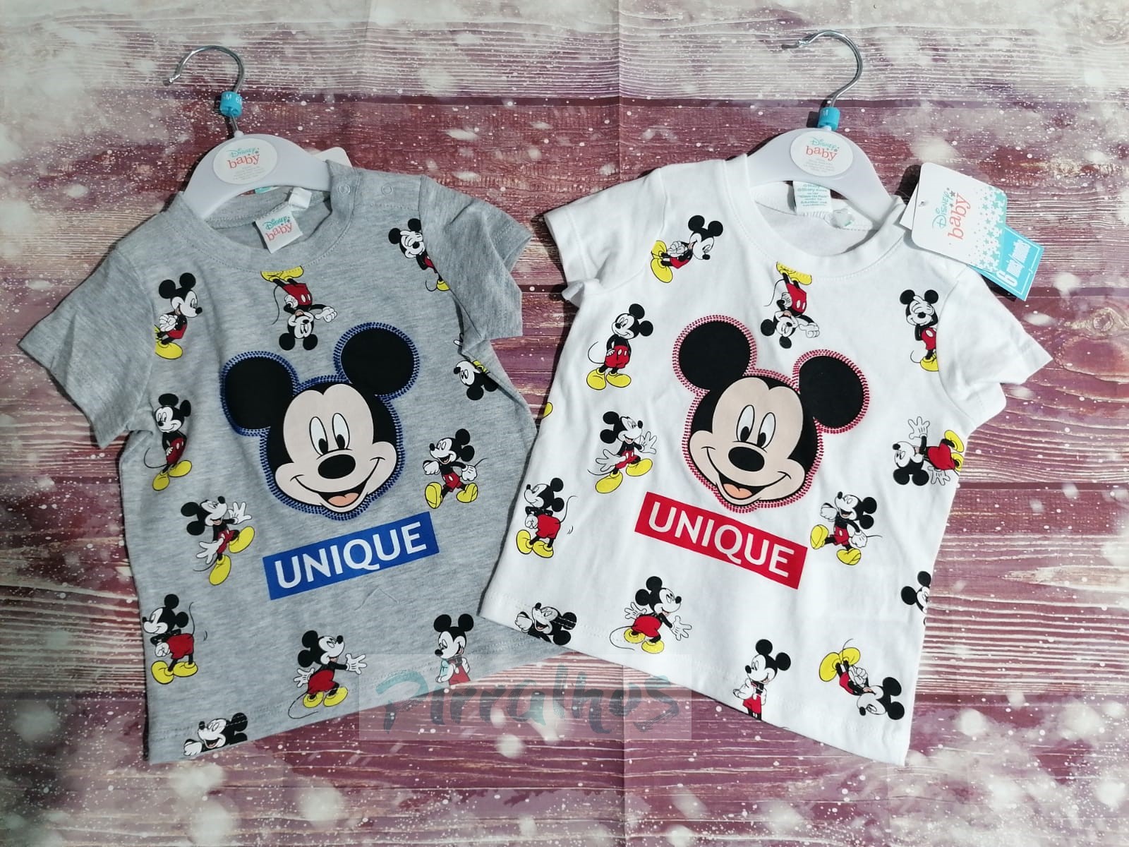 Duas t-shirts infantis cinzenta e branca com padrão do Mickey Mouse e a palavra UNIQUE