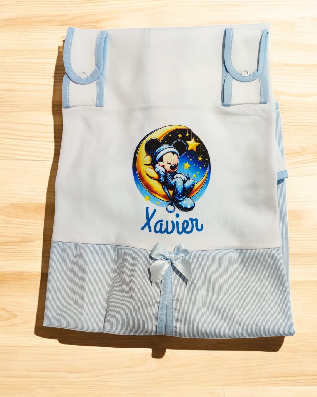 Fralda branca e azul com ilustração de Mickey, nome Xavier e detalhes em fita azul