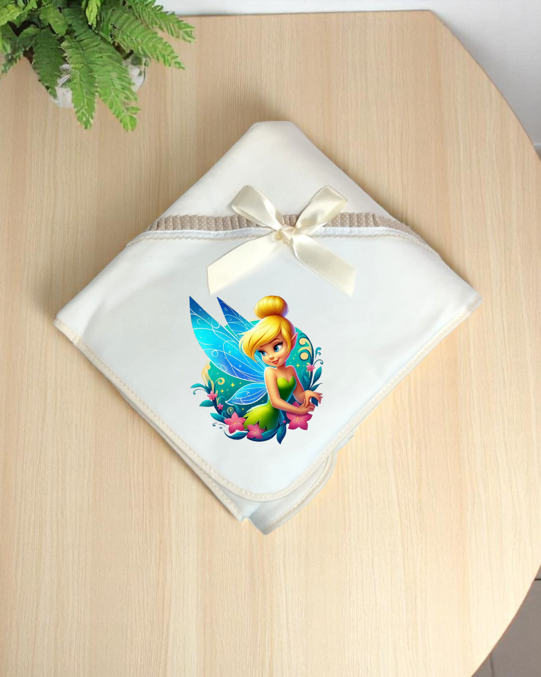 Manta branca para bebé com estampa de fada azul e verde e um laço creme