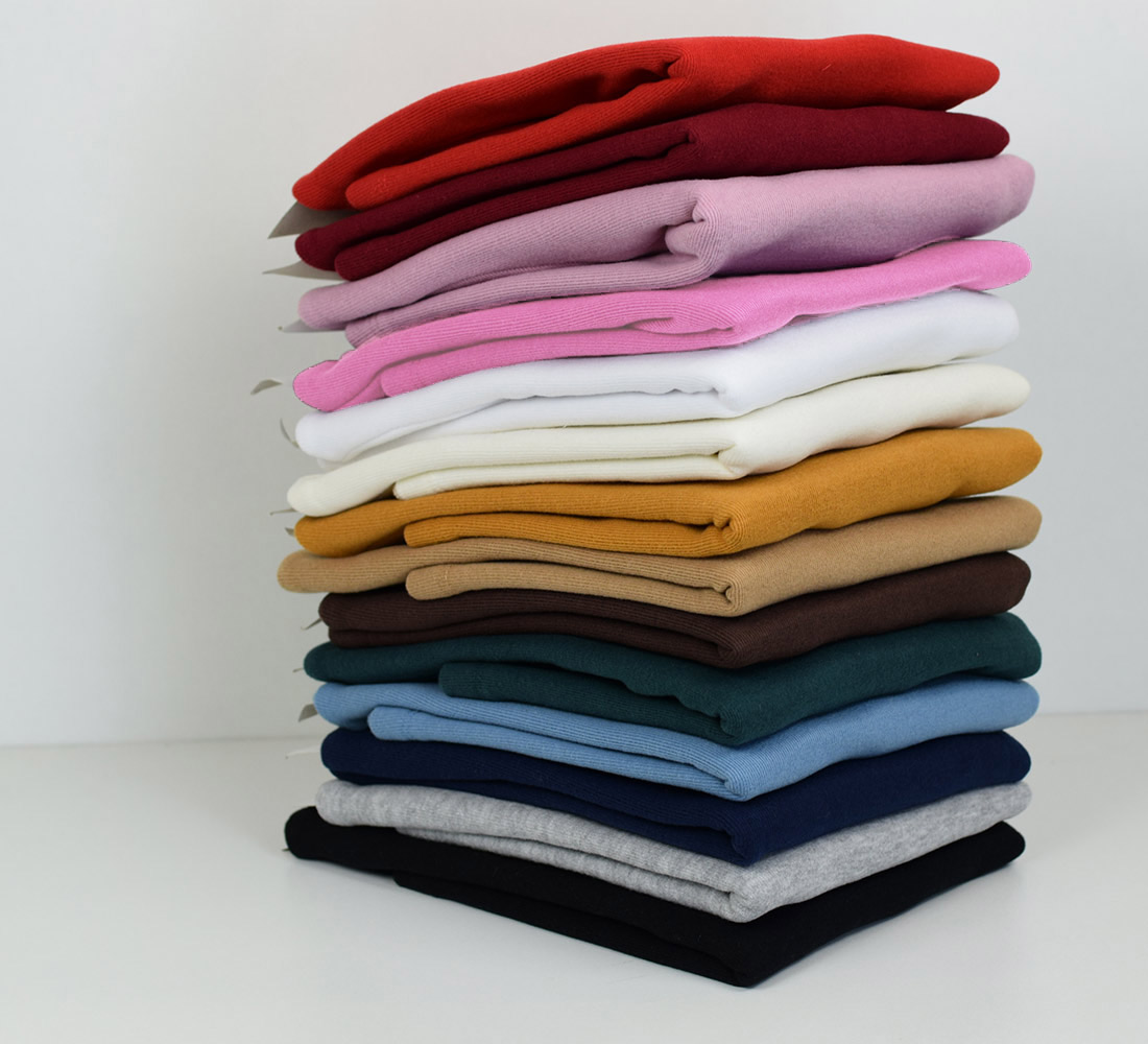 Pilhas de camisolas de malha em várias cores sobre superfície branca