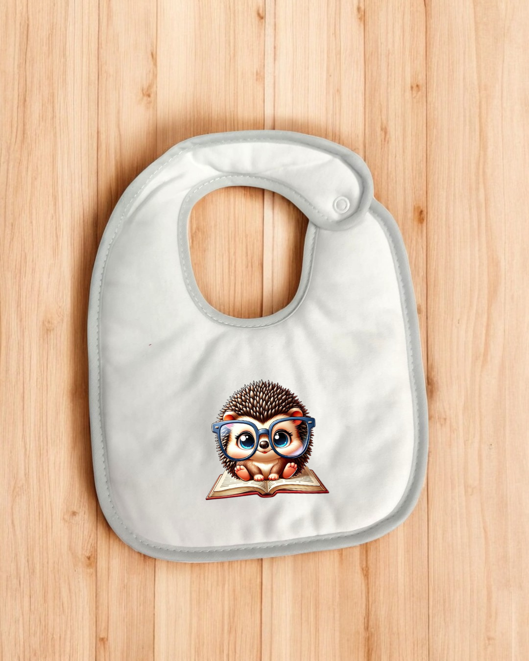 Babete branco com estampa de ouriço a ler e fundo de madeira clara