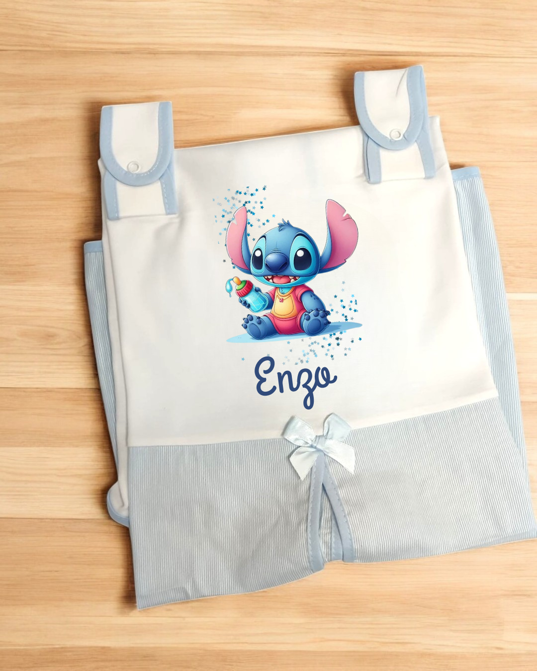 Saco de bebé branco e azul claro com estampa de personagem azul e nome Enzo