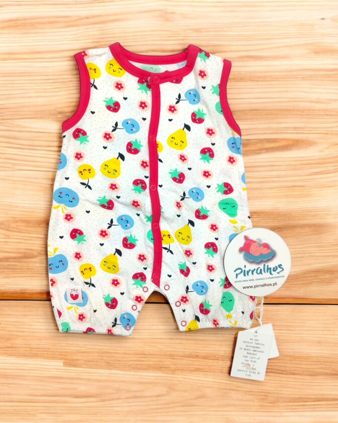 Macacão de bebé branco com padrão de frutas coloridas e detalhes vermelhos