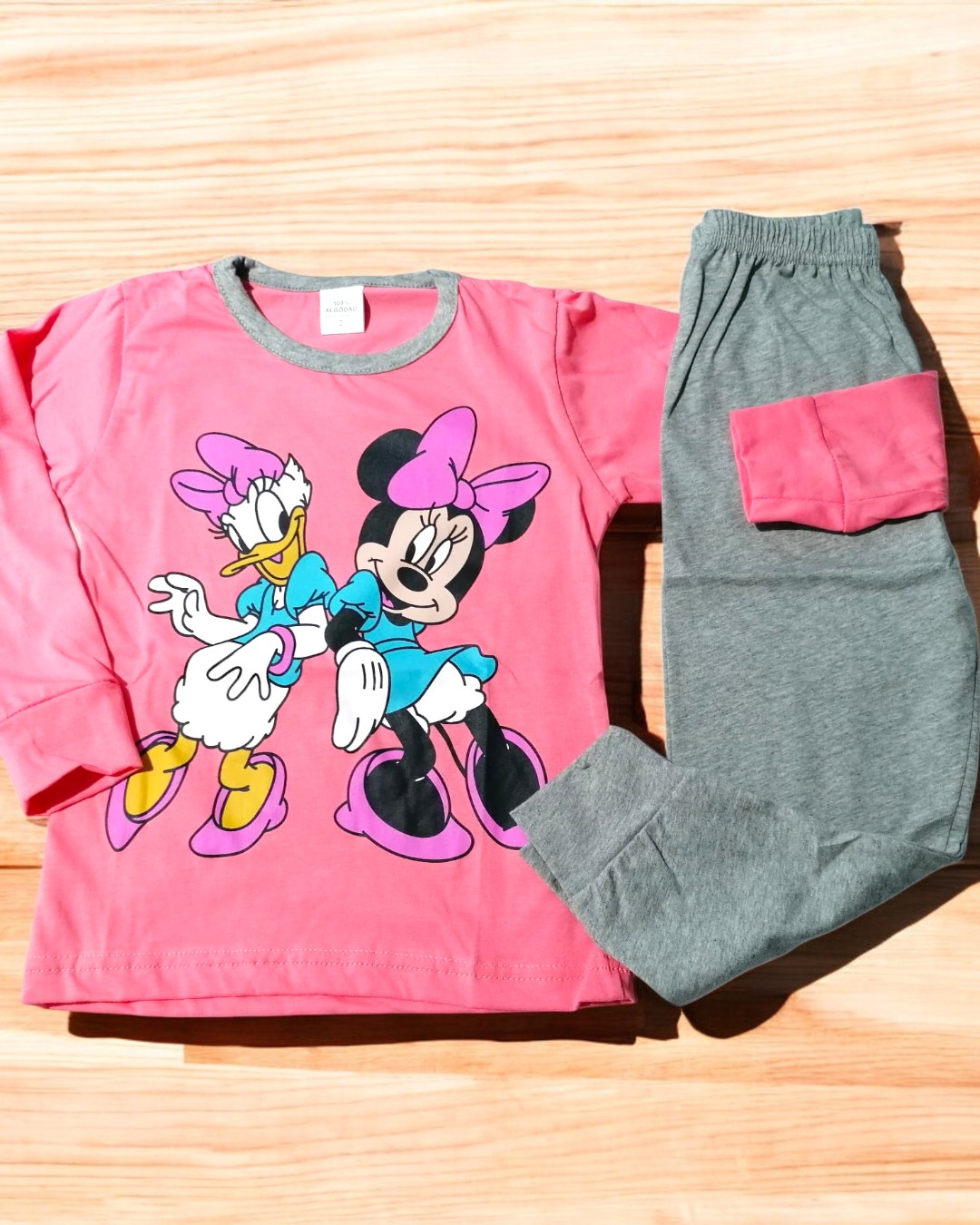 Conjunto de pijama infantil com camisola rosa e calças cinza com bolso rosa