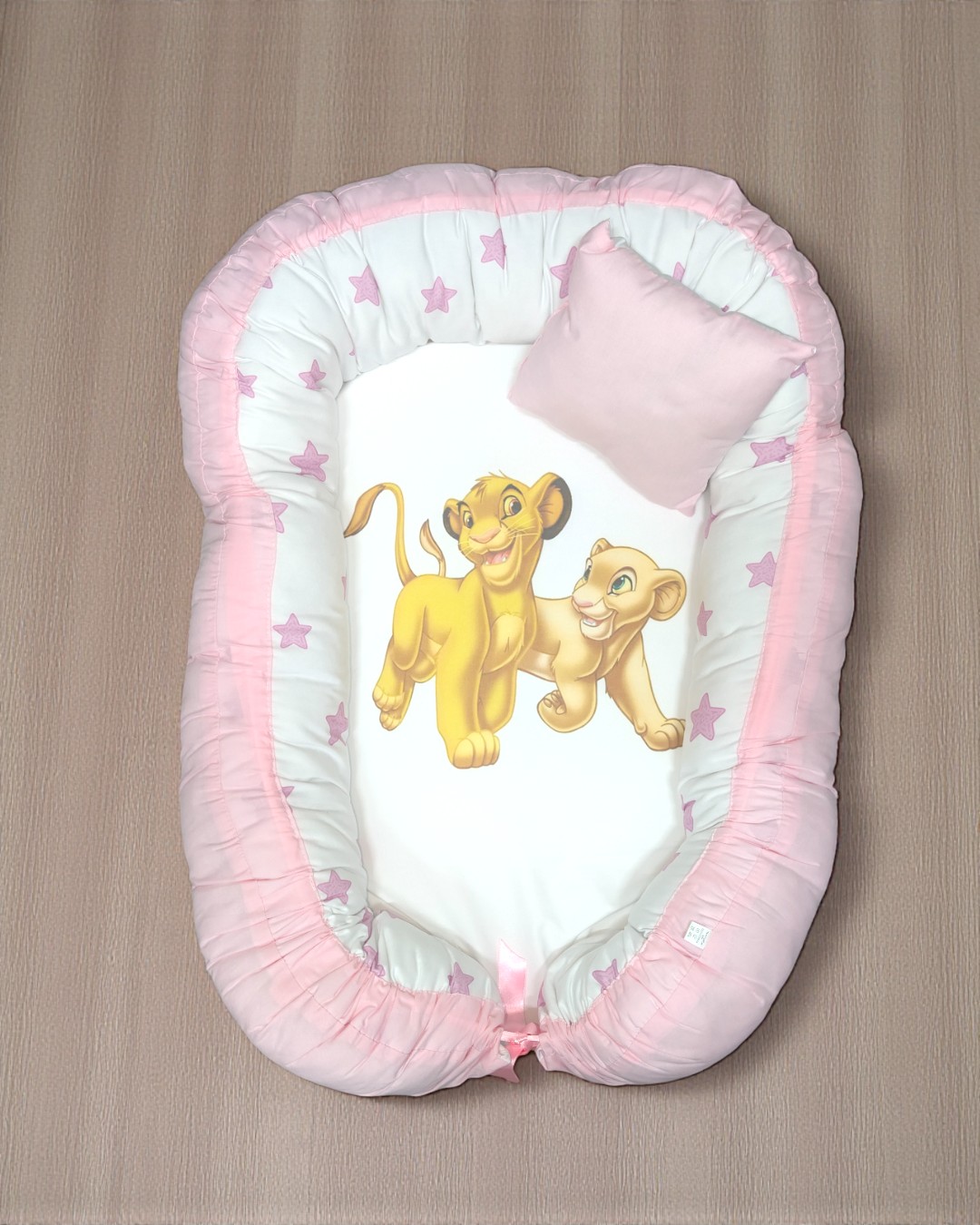 Ninho de bebé rosa e branco com estampado do Rei Leão e almofada pequena