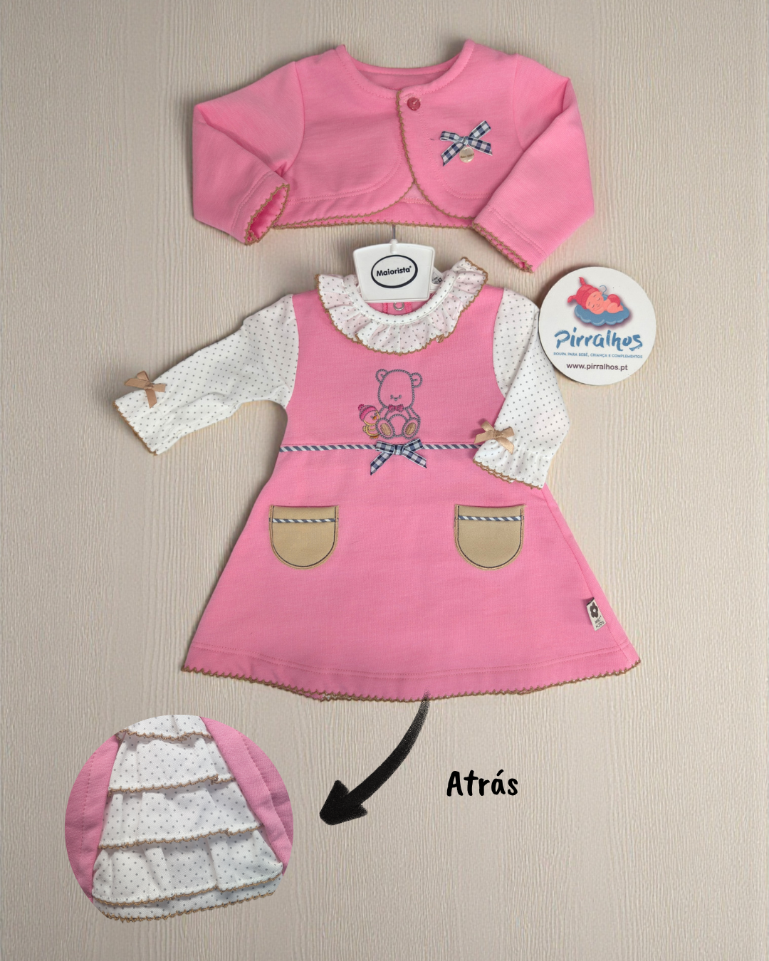 Conjunto de roupa de bebé rosa com vestido e casaco sobre fundo claro