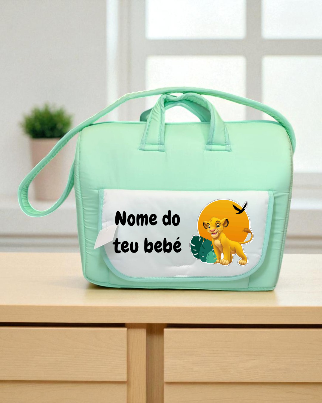 Mala de bebé verde-água com bolso frontal branco com desenho de leão e texto 'Nome do teu bebé'