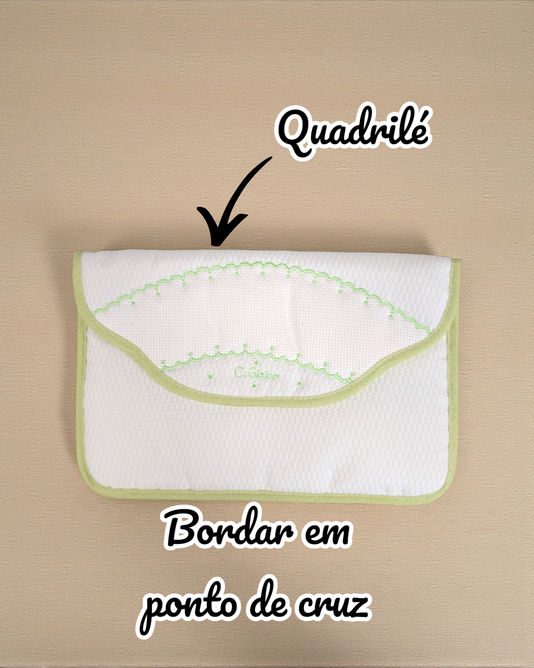 Carteira branca com bordas verdes e bordado em ponto de cruz verde colocado sobre fundo bege