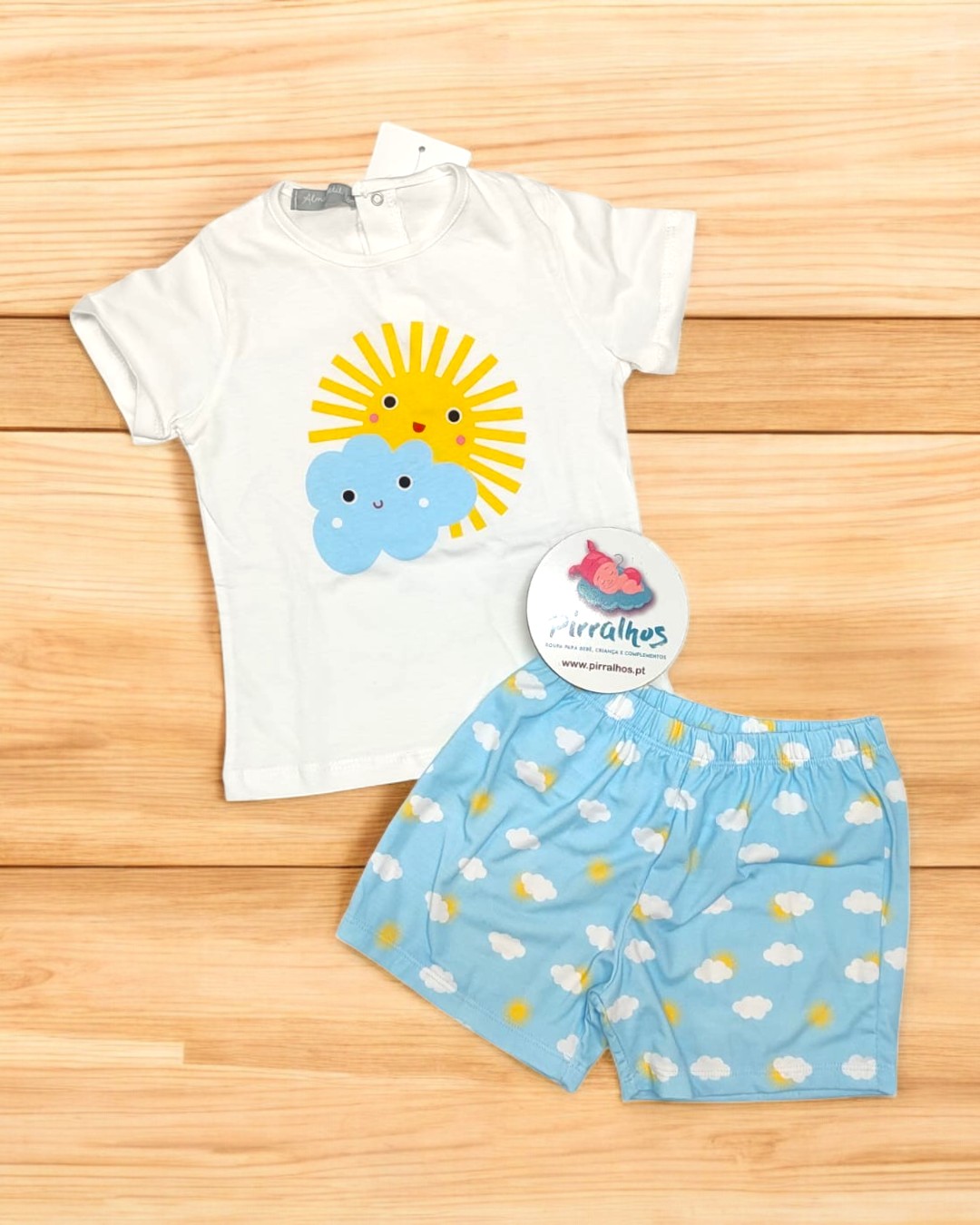 Conjunto infantil com t-shirt branca e calções azuis com padrão de nuvens e sol