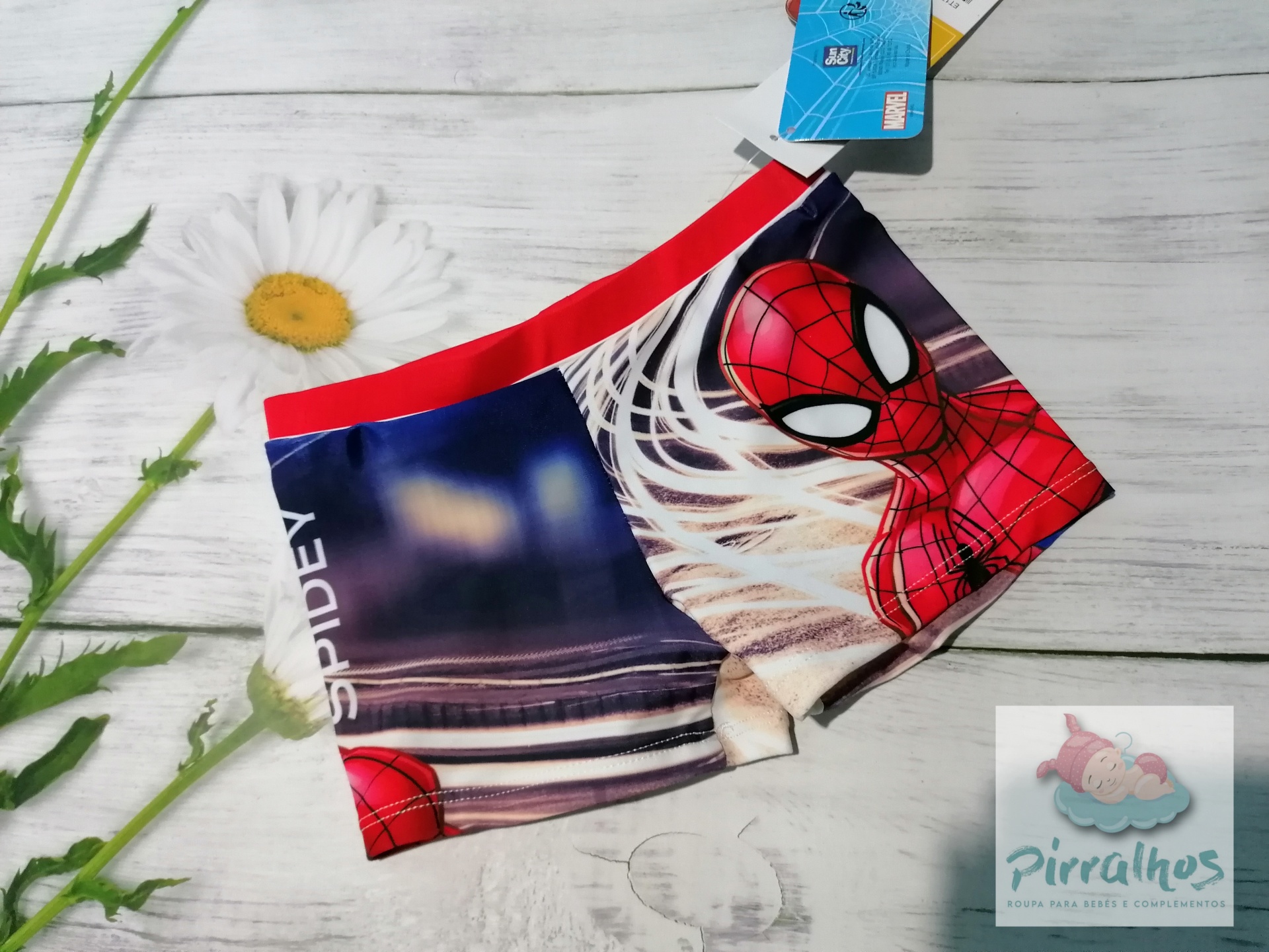 Cuecas boxer infantis Homem-Aranha com elástico vermelho e estampa colorida, sobre superfície decorada com flores