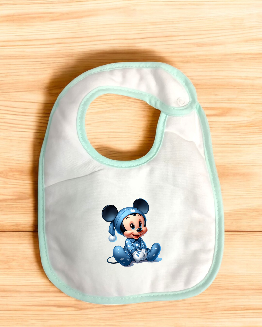 Babete branco com borda verde clara e estampa de bebé Mickey Mouse em pijama azul