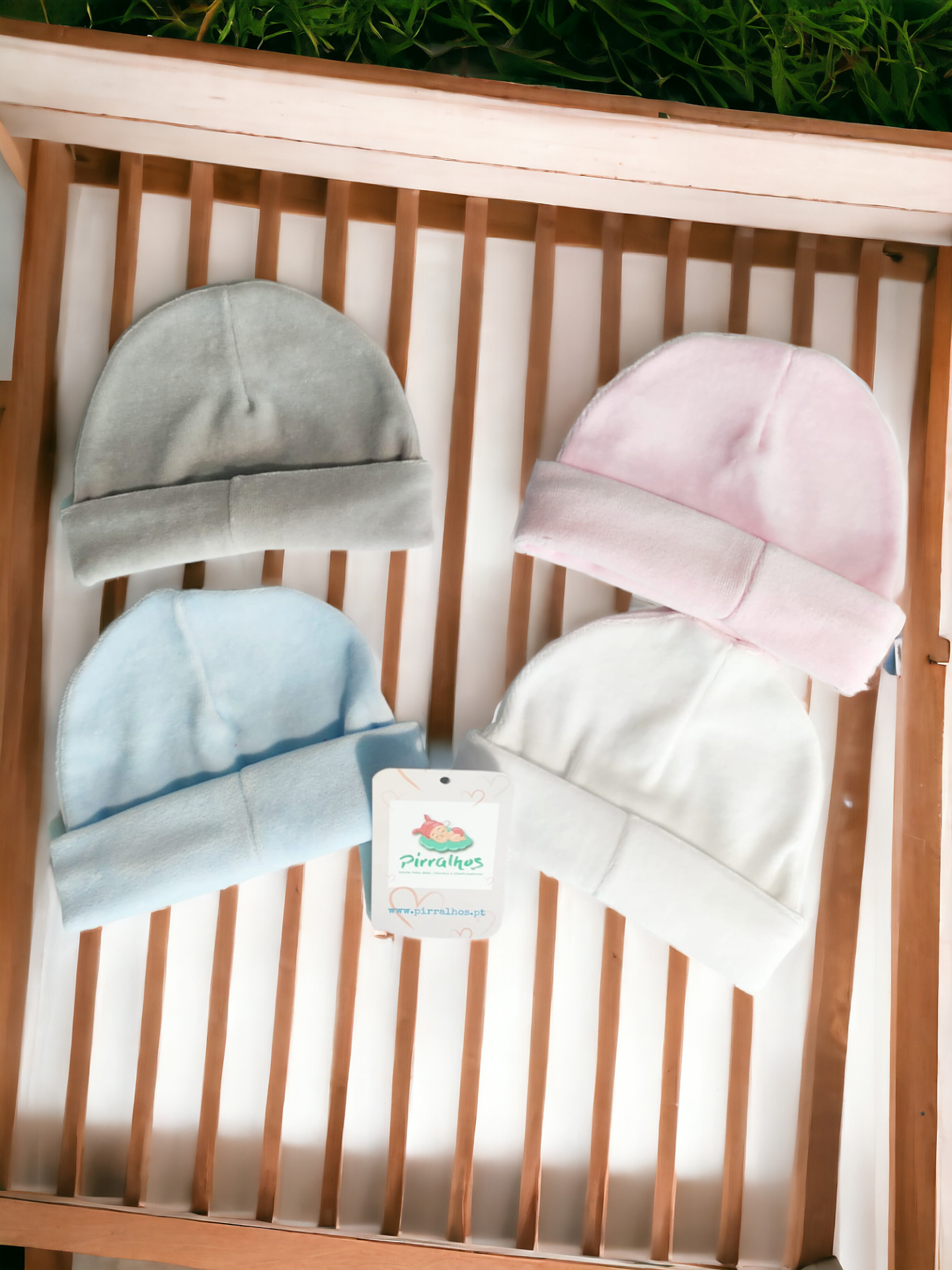 Quatro gorros de bebé em várias cores sobre uma superfície de madeira