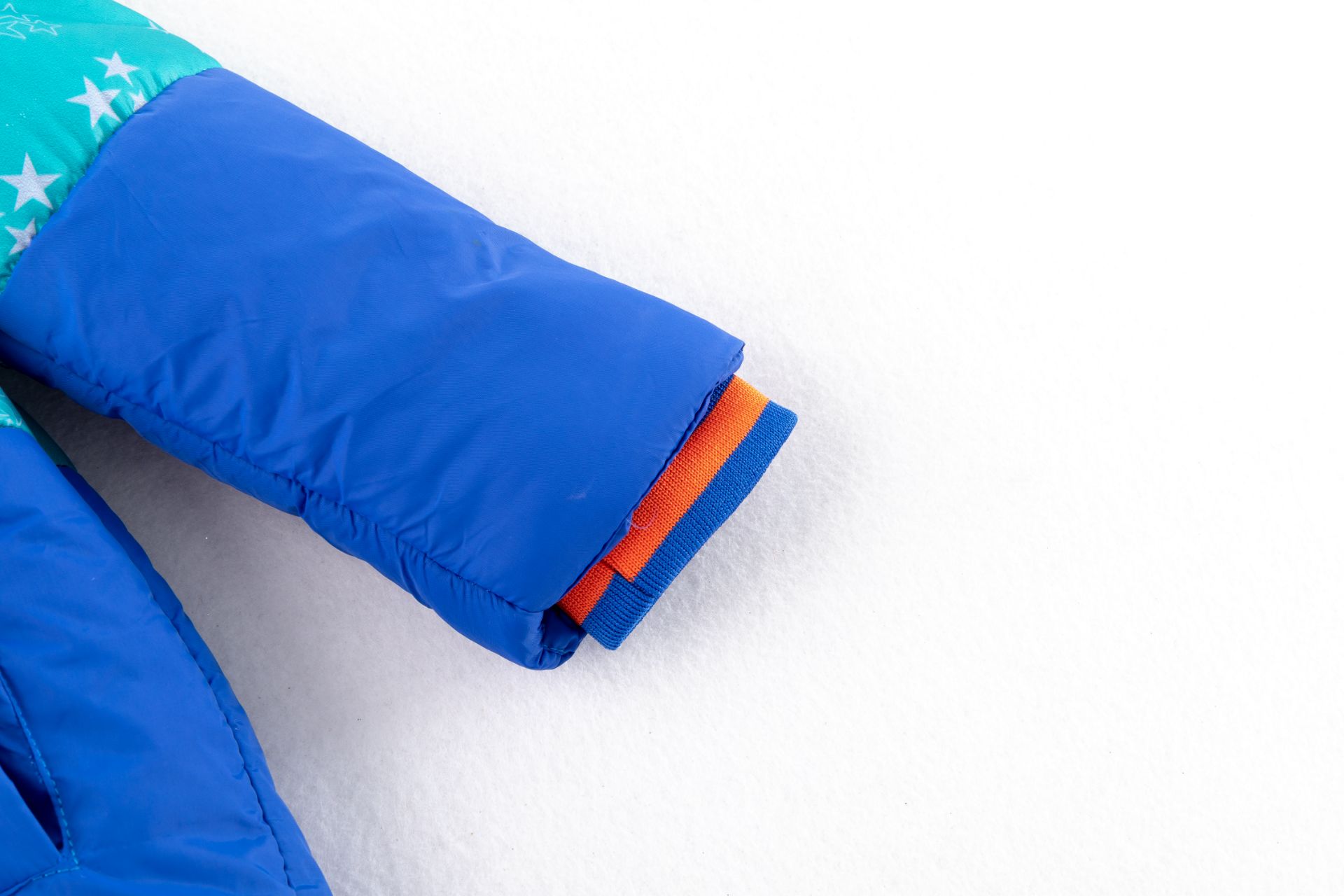 Manga azul de casaco acolchoado com punho laranja e azul e estrelas brancas