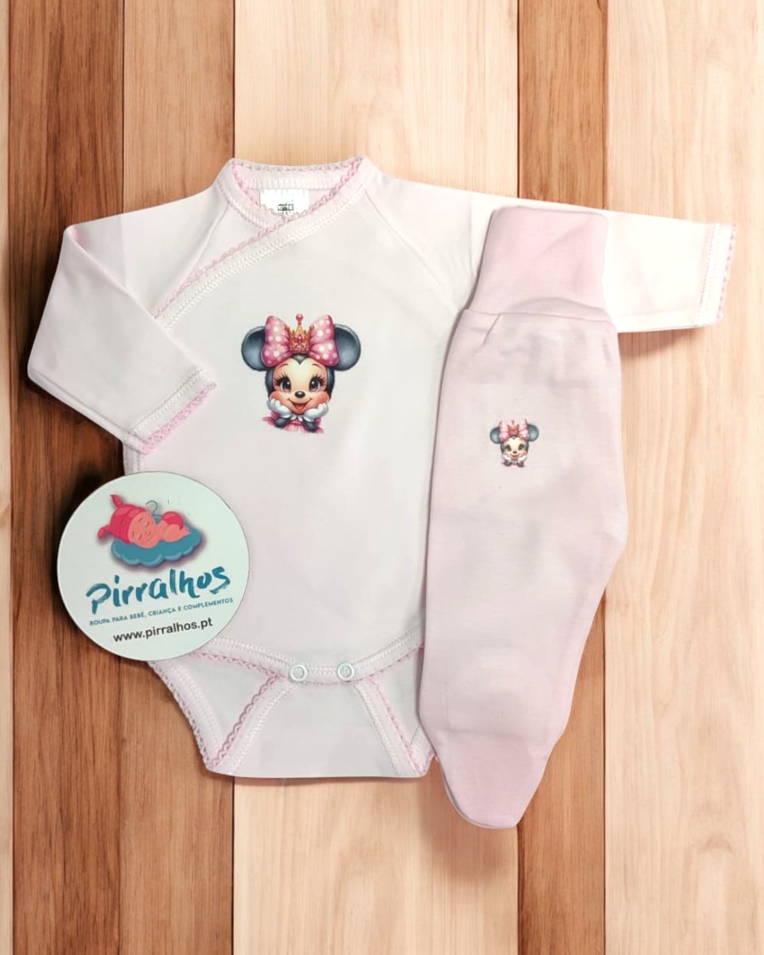 Roupa de bebé com estampa de personagem infantil em fundo de madeira.