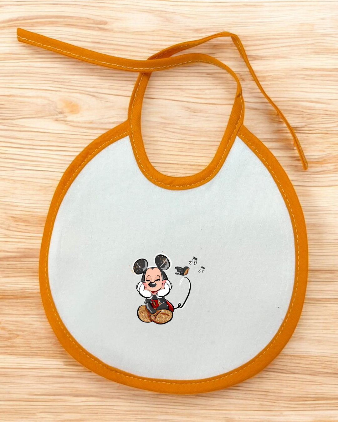 Babete branco com bordas laranja e desenho do Mickey Mouse central