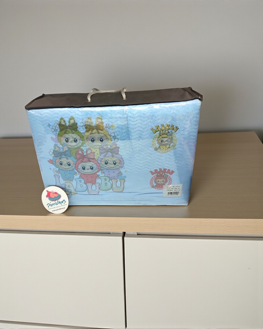 Bolsa azul com personagens animados BUBU e etiqueta Pirulitos sobre móvel de madeira