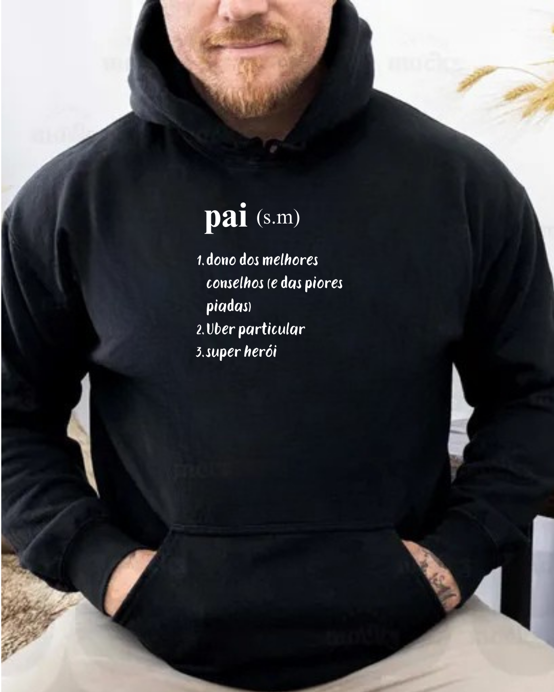 Sweatshirt preta com texto branco sobre 'pai' usada por homem sentado.