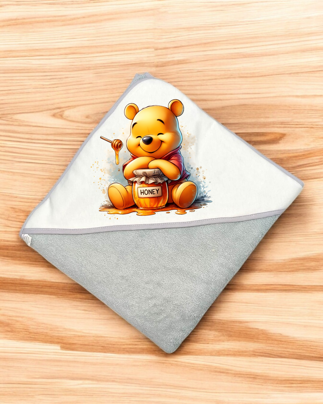 Toalha de bebé cinza e branca com estampa do Ursinho Pooh e pote de mel