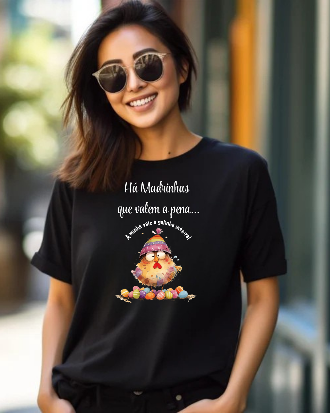 Mulher sorridente com t-shirt preta estampada com galinha e texto em português e óculos de sol