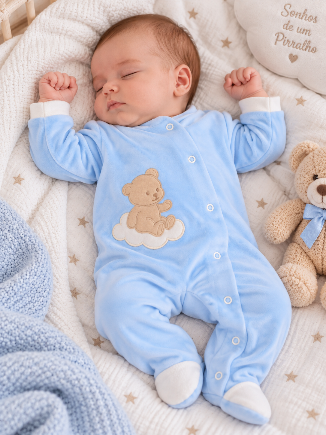 bebé a dormir com pijama azul e ursinho bordado numa cama com colcha de estrelas e manta azul