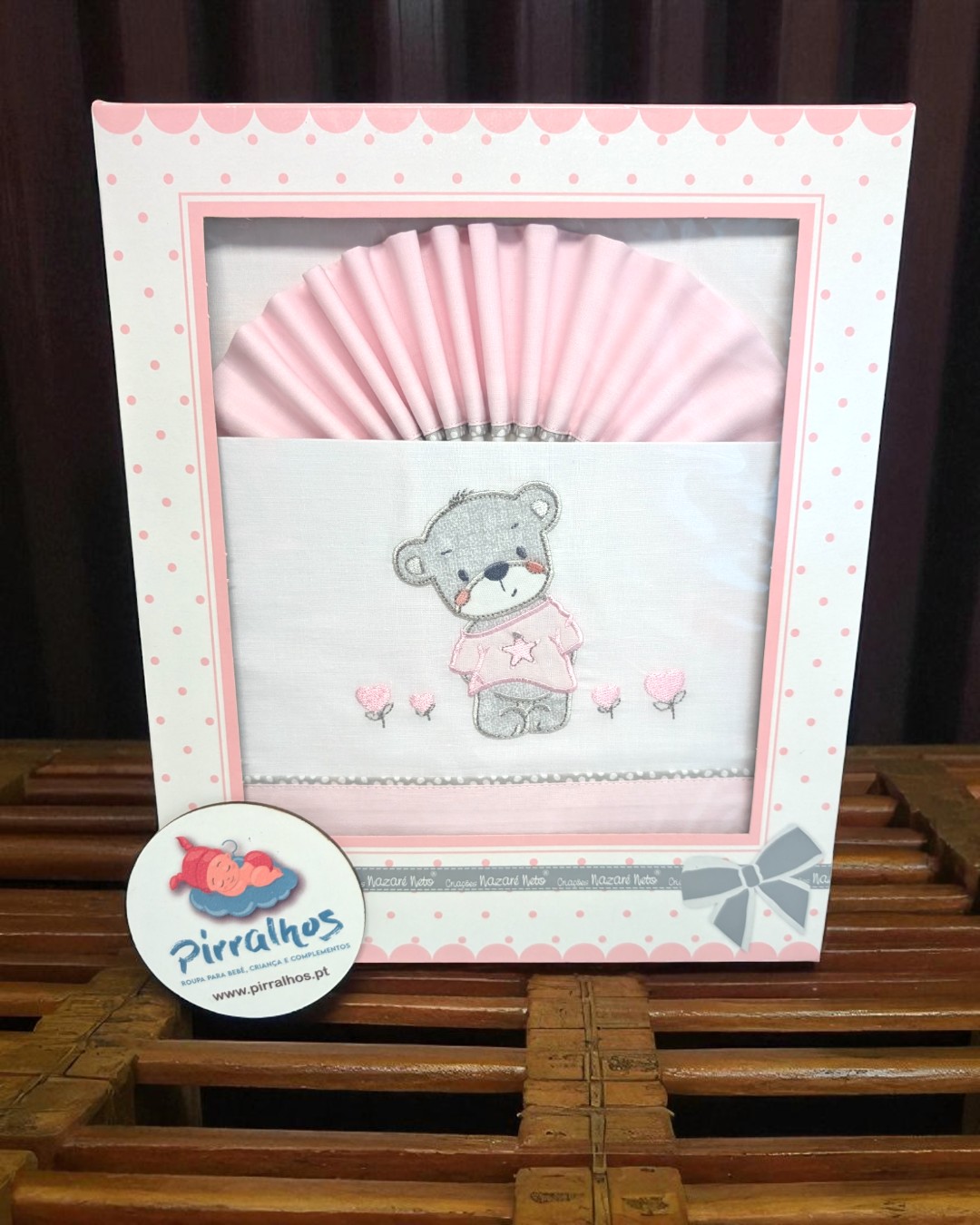 Conjunto para bebé com biberão e tecido rosa decorado com ursinho e flores, numa caixa branca com bolinhas cor de rosa.