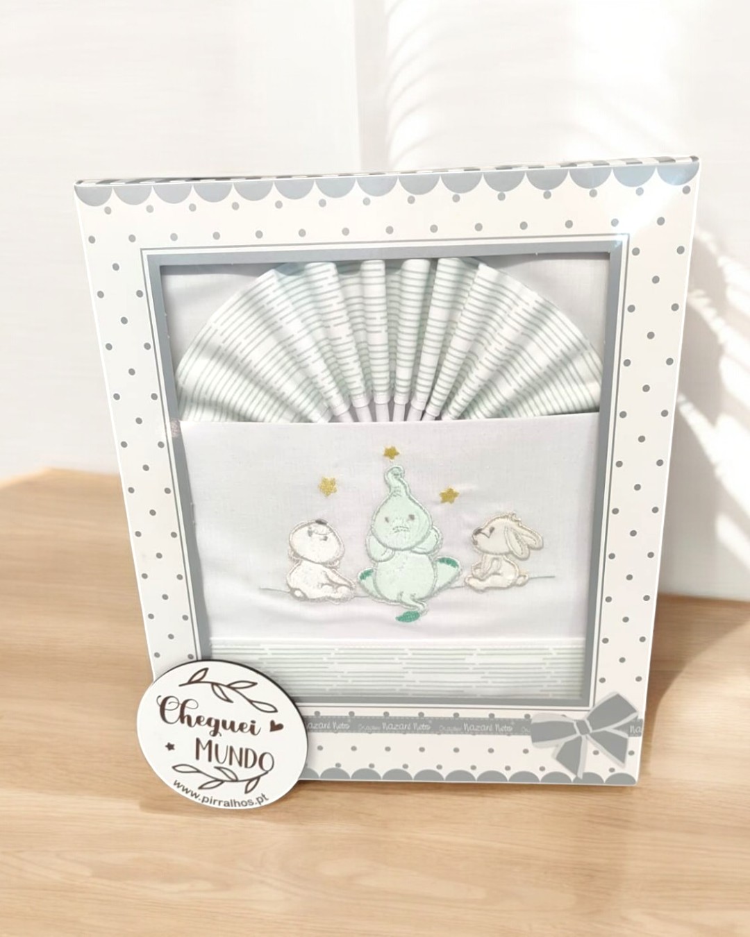 Conjunto de fraldas de bebé com bordado de animais e estrela em caixa branca com bolinhas cinzentas.