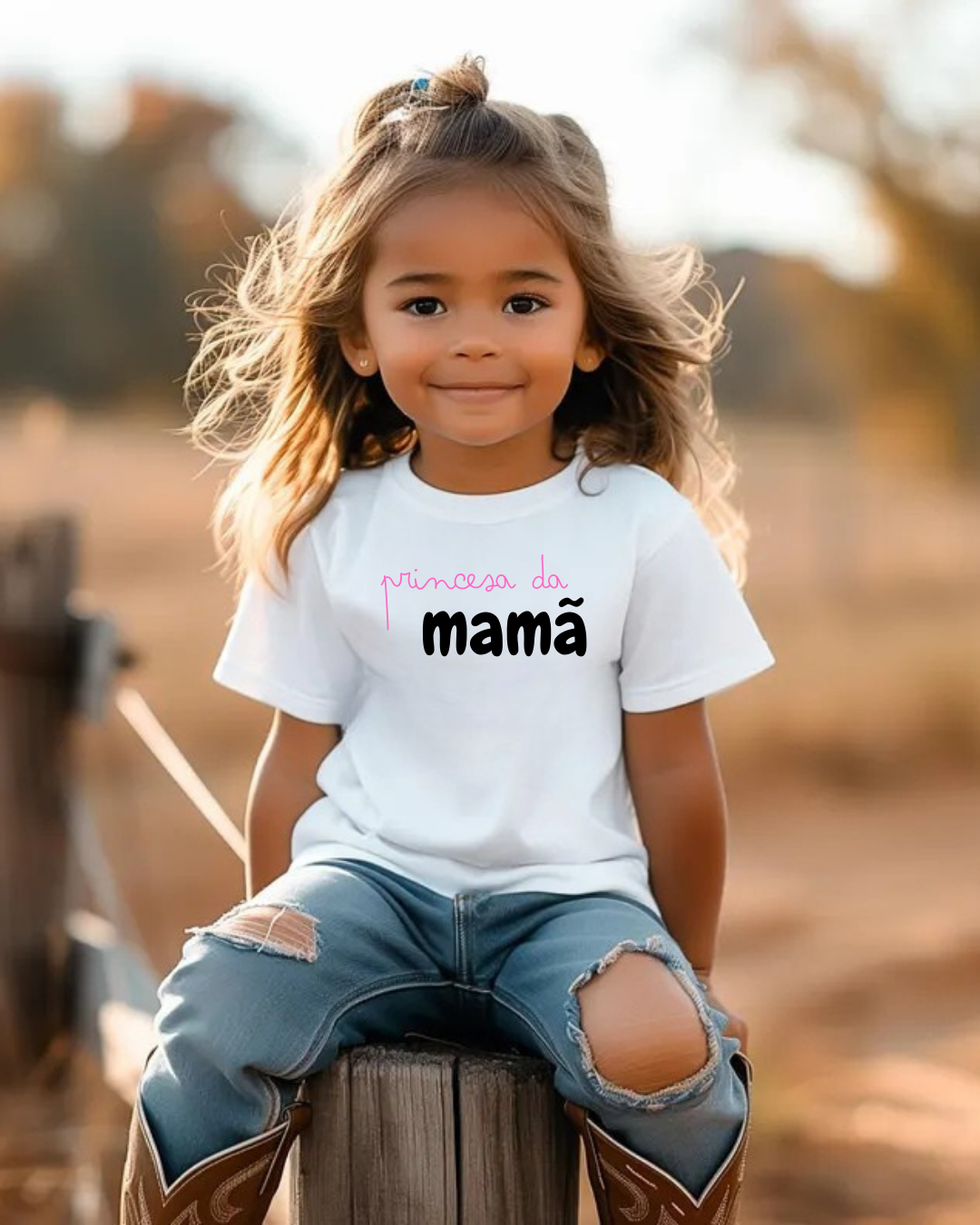 Menina sentada numa cerca de madeira a usar camisola branca com texto e calças azuis rasgadas